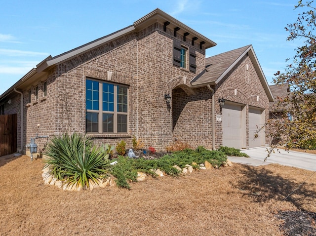 view of front of home with a garage, brick siding, and driveway