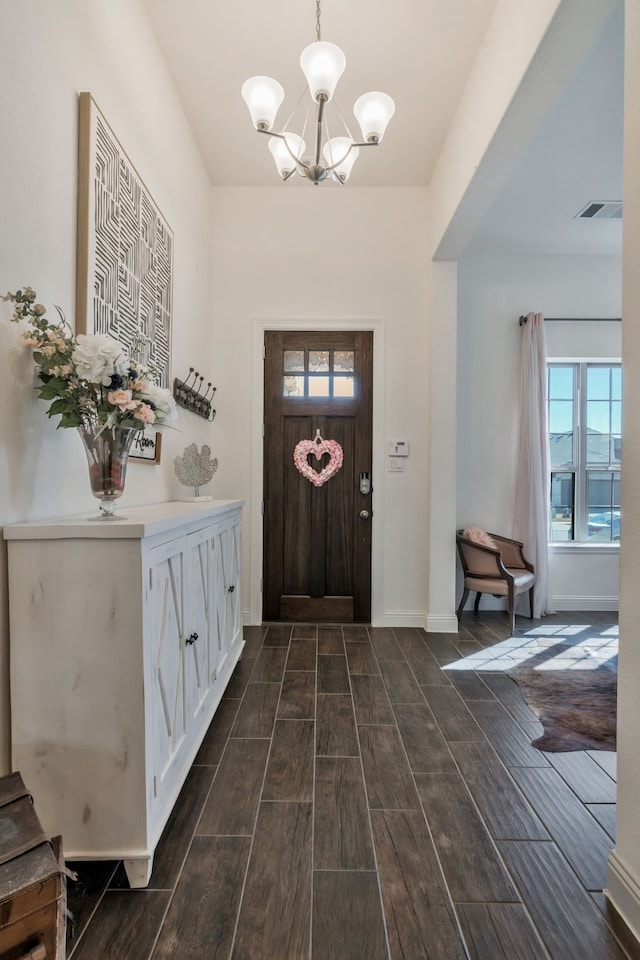 entrance foyer with a notable chandelier, visible vents, a healthy amount of sunlight, and wood tiled floor