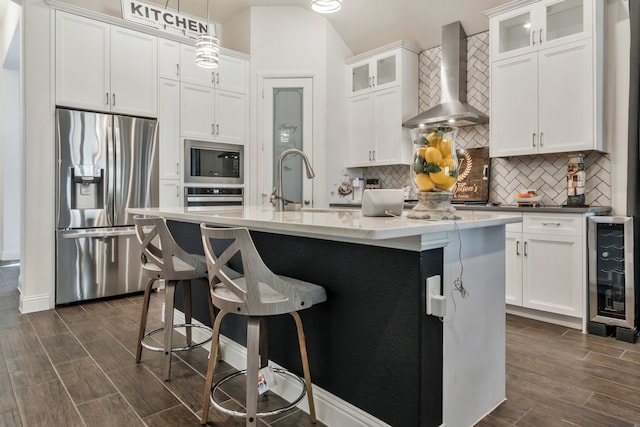 kitchen featuring tasteful backsplash, appliances with stainless steel finishes, wall chimney exhaust hood, and wood tiled floor