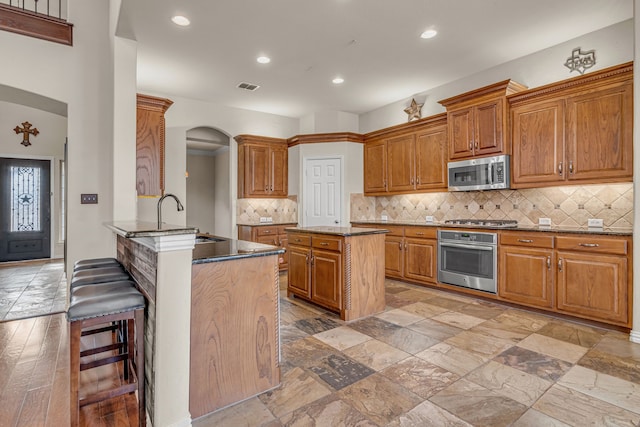 kitchen featuring brown cabinetry, visible vents, appliances with stainless steel finishes, and a sink