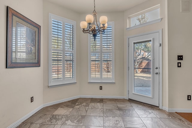 entryway featuring baseboards, a notable chandelier, and marble finish floor