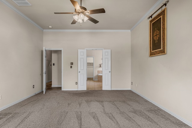 unfurnished bedroom featuring baseboards, visible vents, carpet floors, crown molding, and connected bathroom