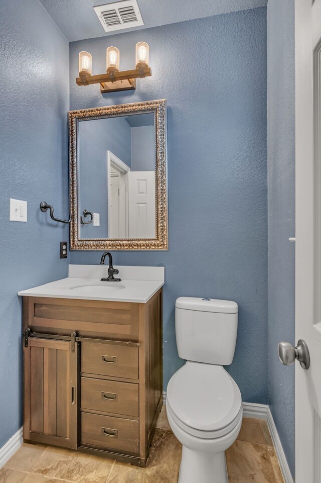 bathroom with vanity, toilet, baseboards, and visible vents