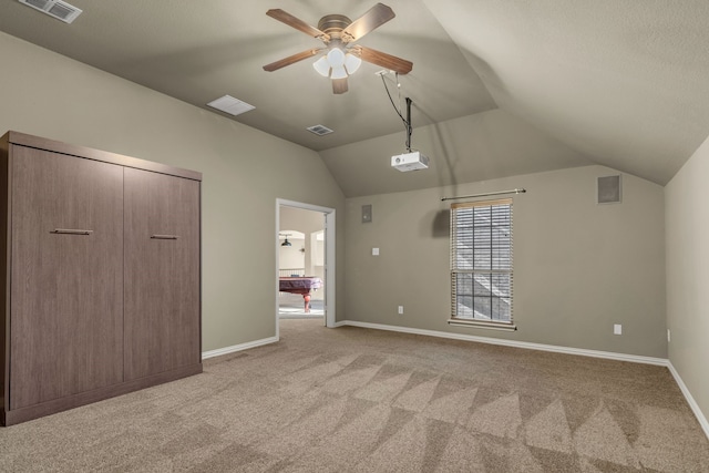 interior space with vaulted ceiling, light colored carpet, visible vents, and baseboards