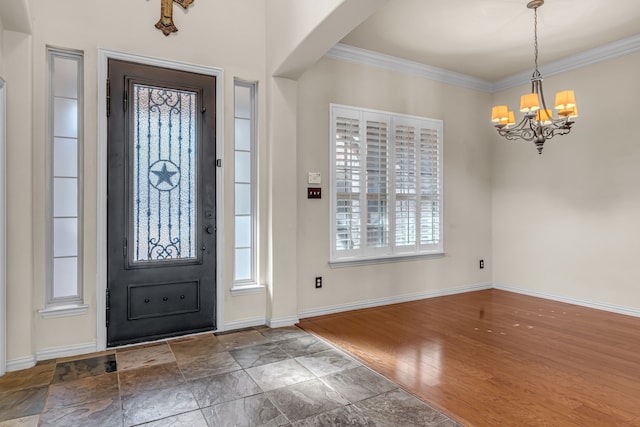 foyer featuring an inviting chandelier, crown molding, baseboards, and wood finished floors