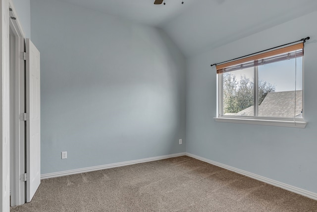 carpeted empty room featuring baseboards and lofted ceiling