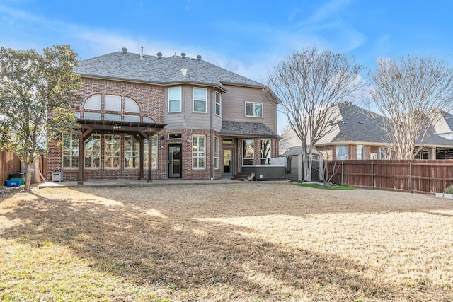 rear view of property featuring a fenced backyard, a shingled roof, an outdoor structure, a storage unit, and brick siding