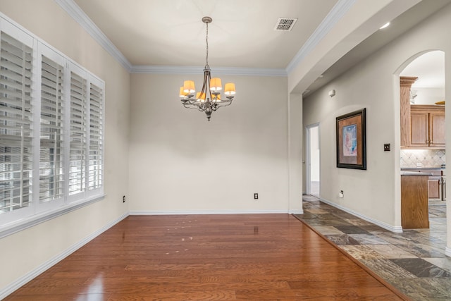 unfurnished dining area featuring an inviting chandelier, wood finished floors, baseboards, and ornamental molding