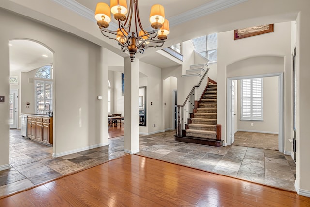 foyer with arched walkways, ornamental molding, and wood-type flooring