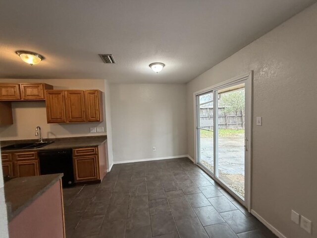 kitchen with baseboards, visible vents, a sink, black dishwasher, and dark countertops