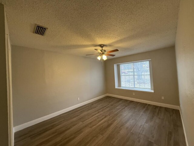 empty room featuring visible vents, baseboards, dark wood finished floors, a textured ceiling, and a ceiling fan