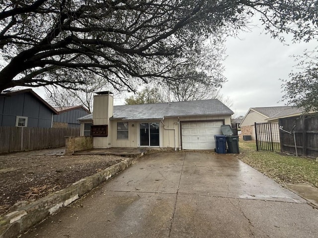 view of front of house featuring a chimney, concrete driveway, a garage, and fence