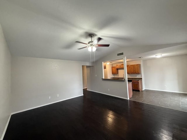 unfurnished living room with baseboards, visible vents, ceiling fan, vaulted ceiling, and dark wood-type flooring