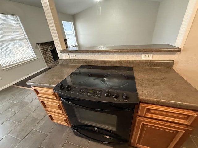 kitchen with dark countertops, baseboards, wood tiled floor, brown cabinets, and electric range