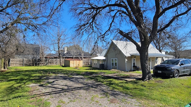 view of property exterior featuring an outbuilding, a storage unit, a lawn, and fence