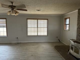 unfurnished living room featuring plenty of natural light, crown molding, and wood finished floors