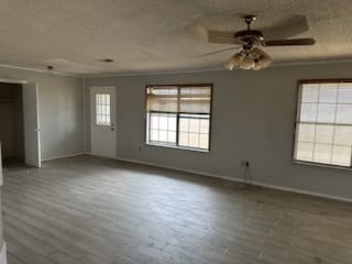 spare room featuring baseboards, ornamental molding, wood finished floors, a textured ceiling, and a ceiling fan