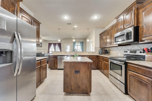 kitchen with visible vents, a peninsula, appliances with stainless steel finishes, backsplash, and a center island