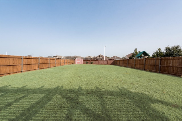 view of yard featuring an outbuilding, a fenced backyard, and a shed