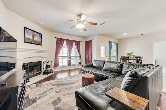 living area with visible vents, a fireplace with raised hearth, a ceiling fan, wood finished floors, and recessed lighting