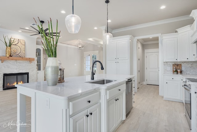 kitchen with tasteful backsplash, ornamental molding, a stone fireplace, appliances with stainless steel finishes, and a sink