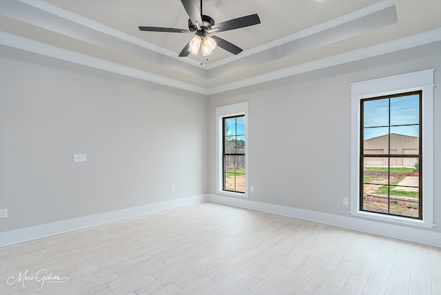 unfurnished room featuring light wood-type flooring, a raised ceiling, crown molding, baseboards, and ceiling fan