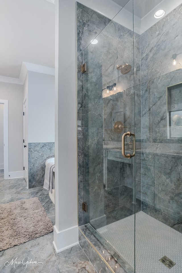 bathroom with marble finish floor, a stall shower, baseboards, and ornamental molding