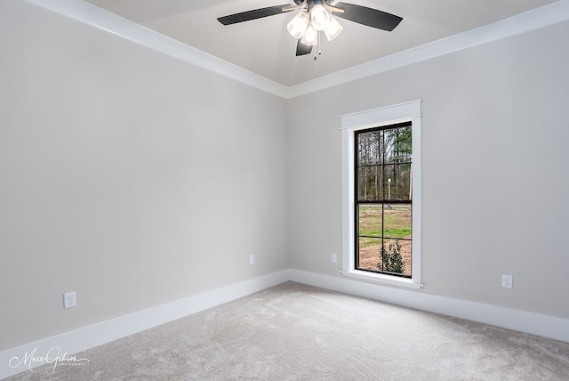 carpeted empty room featuring baseboards, a ceiling fan, and crown molding