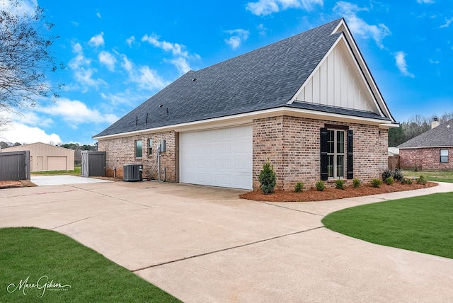 view of side of home with roof with shingles, brick siding, central AC, a garage, and board and batten siding