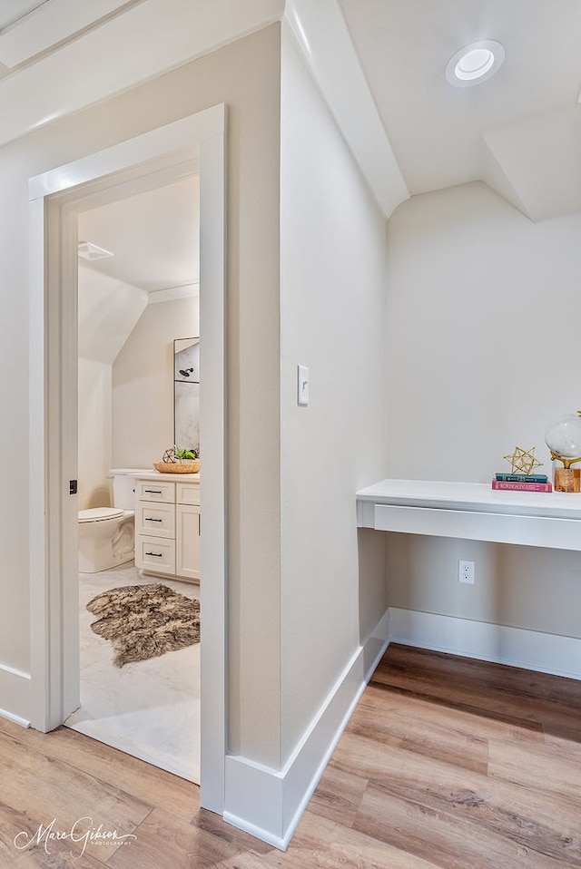 interior space featuring baseboards, light wood-type flooring, and lofted ceiling