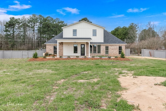 back of house with brick siding, a lawn, and fence