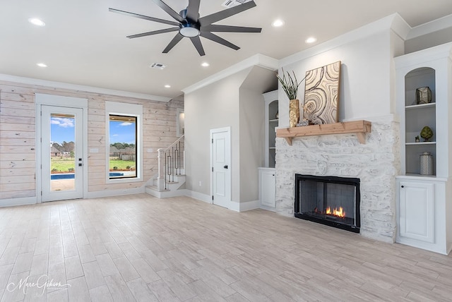 unfurnished living room featuring visible vents, ornamental molding, stairway, a fireplace, and light wood finished floors