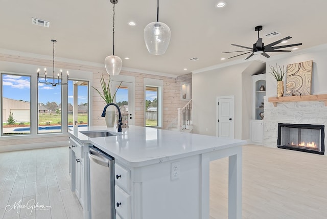 kitchen featuring visible vents, a sink, stainless steel dishwasher, open floor plan, and a lit fireplace