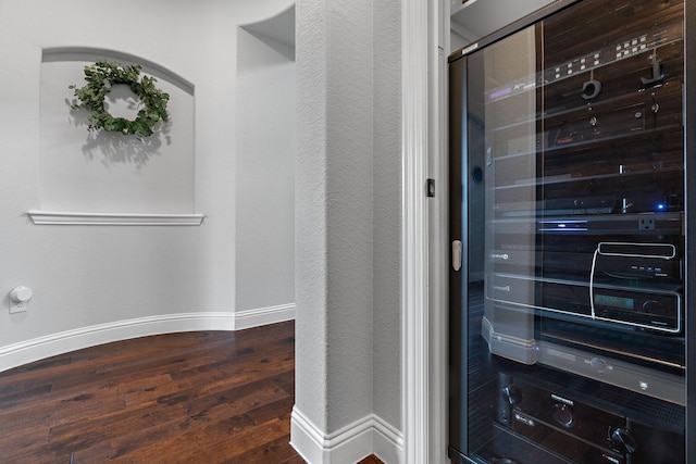 interior details featuring wood finished floors, beverage cooler, baseboards, and a textured wall