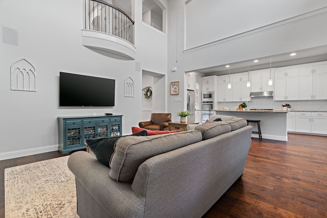 living room featuring recessed lighting, a high ceiling, baseboards, and dark wood-style flooring