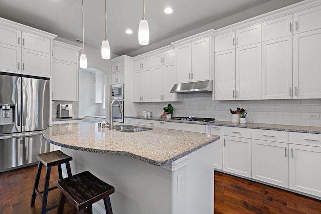 kitchen with visible vents, a sink, under cabinet range hood, appliances with stainless steel finishes, and a kitchen bar