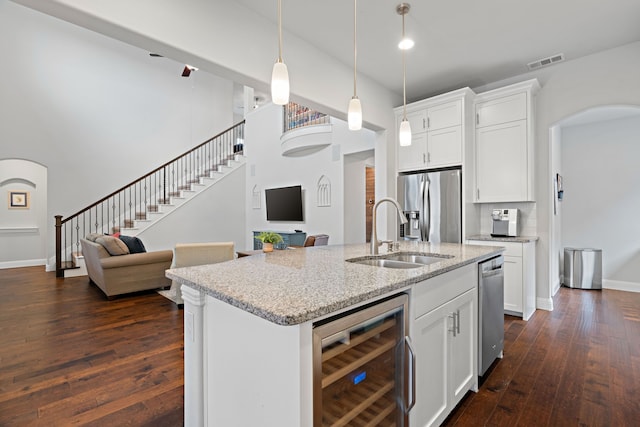 kitchen featuring visible vents, a sink, open floor plan, stainless steel appliances, and wine cooler