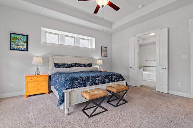 bedroom with ensuite bath, a raised ceiling, baseboards, and carpet floors