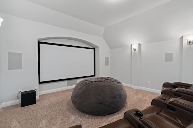 carpeted home theater with lofted ceiling and baseboards