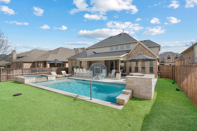 view of swimming pool featuring a lawn, a patio, a pool with connected hot tub, and a fenced backyard