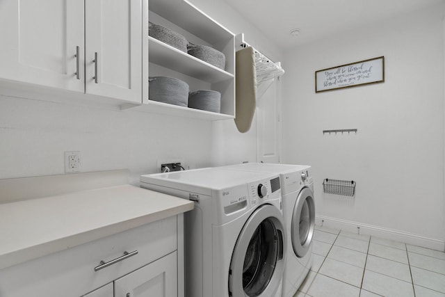 washroom with cabinet space, washer and dryer, baseboards, and light tile patterned flooring