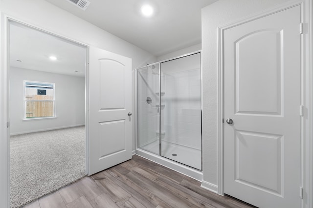 bathroom featuring a shower stall, wood finished floors, visible vents, and baseboards