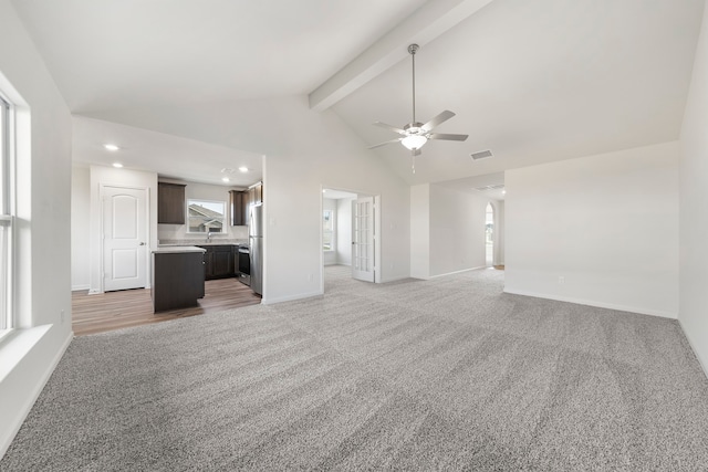 unfurnished living room with beam ceiling, visible vents, light carpet, and baseboards