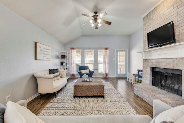 living area featuring lofted ceiling, wood finished floors, a fireplace, baseboards, and ceiling fan