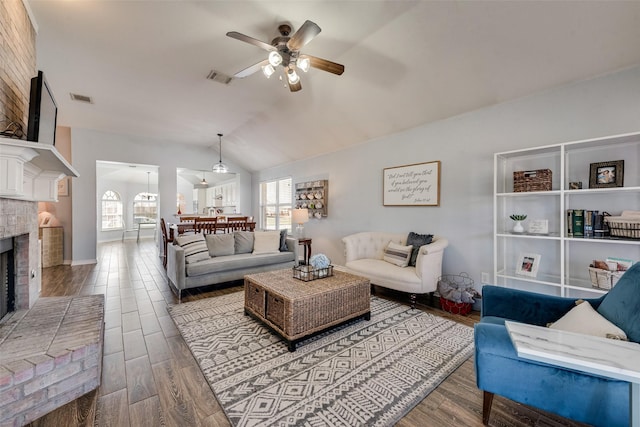 living room with visible vents, a fireplace, lofted ceiling, and wood finished floors