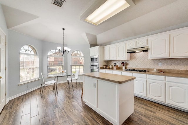 kitchen featuring dark wood-style floors, visible vents, stainless steel appliances, decorative backsplash, and under cabinet range hood