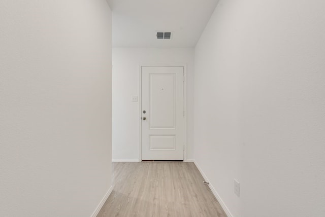 hall featuring visible vents, baseboards, and light wood-style flooring