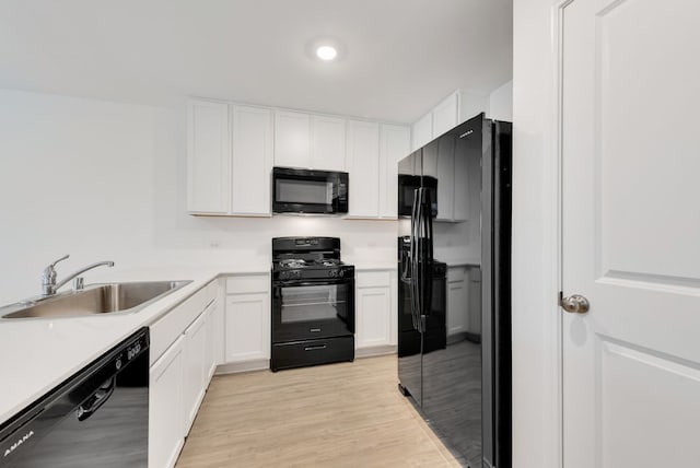 kitchen with white cabinetry, black appliances, and a sink