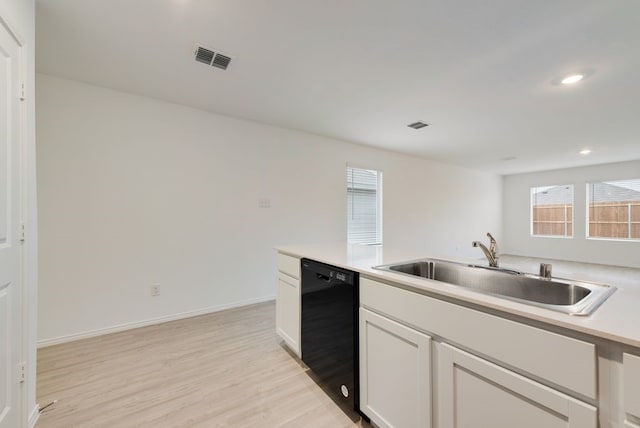 kitchen featuring visible vents, a sink, black dishwasher, white cabinetry, and light wood finished floors