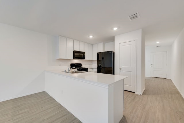 kitchen featuring visible vents, black appliances, a sink, a peninsula, and light countertops